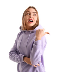 Surprised young woman in lilac hoodie pointing at something on white background