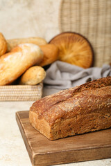 Cutting board with loaf of rye bread on white table
