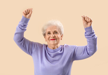 Senior woman in lilac sweater dancing on beige background