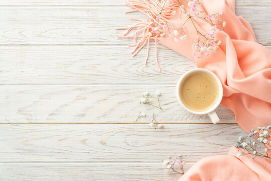 Hello spring concept. Top view photo of cup of cocoa gypsophila flowers and pink plaid on grey wooden desk background with copyspace
