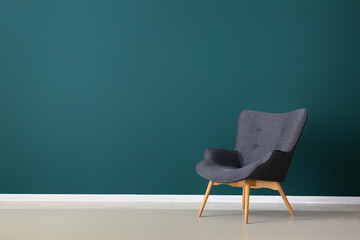 Stylish grey armchair near green wall