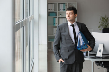 Fototapeta premium Young accountant with folders in office