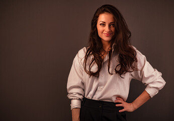 Beautiful business happy smiling woman with long brown healthy hair style standing with folded arms in white stripped shirt. Success business. Closeup front portrait. Toned vintage color