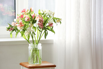 Vase with beautiful alstroemeria flowers on table near window in room