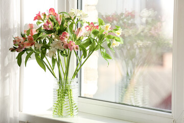 Vase with beautiful alstroemeria flowers on windowsill in room