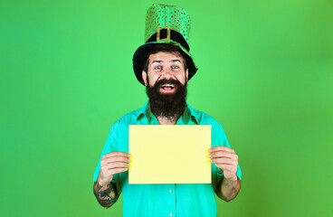 Saint Patrick's Day. Happy bearded man in leprechaun green hat with advertising board. Man dressed...