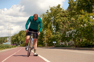 Fototapeta premium Handsome muscular cyclist standing with bike
