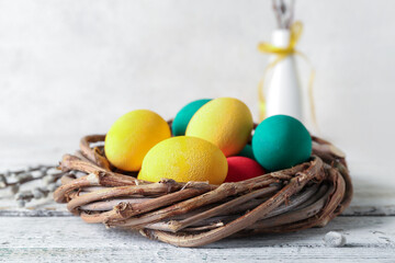 Wreath with painted Easter eggs on light wooden table