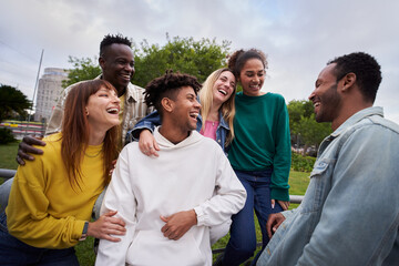 Young group of cheerful multiracial friends looking at each other and laughing outdoors. Concept of...