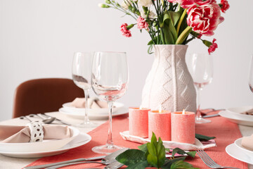 Beautiful setting for International Women's Day celebration with burning candles, glasses and flowers on table