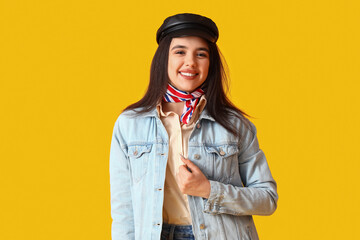 Fototapeta premium Stylish young woman in cap on yellow background