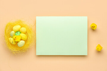 Blank greeting card, nest with Easter eggs and baby chickens on beige background
