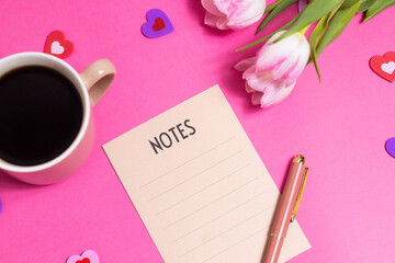Notes with pen, cup of coffee, tulip spring flower and cute hearts on pink background, flat lay