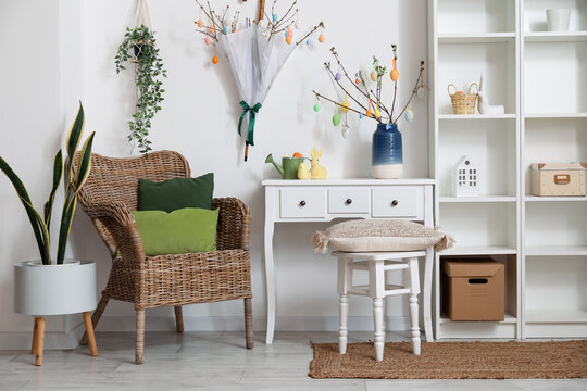 Interior of light living room with Easter decor, armchair and shelving unit