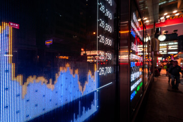 Financial stock exchange market display screen board on the street with and city light reflections, selective focus