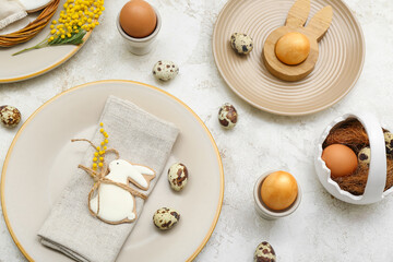 Table setting with Easter eggs and mimosa flowers on white grunge background