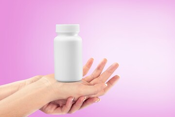 Young hand holding plastic bottle with pills