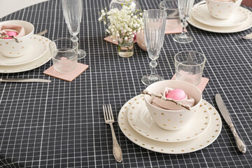 Festive table setting with painted eggs and gypsophila flowers served for Easter celebration