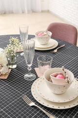 Festive table setting with painted eggs and gypsophila flowers served for Easter celebration