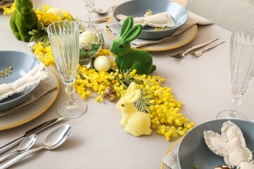 Festive table setting with eggs, bunnies and mimosa flowers served for Easter celebration