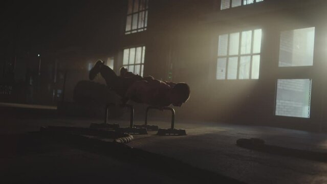 Handheld shot of a shirtless handsome caucasian sportsman doing handstand exercise in an abandoned warehouse. Bodyweight exercise