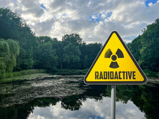 Radioactive pollution. Yellow warning sign with hazard symbol near contaminated area outdoors....