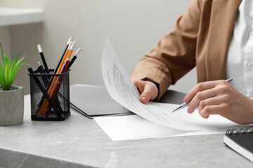 Woman signing document at light grey marble table in office, closeup
