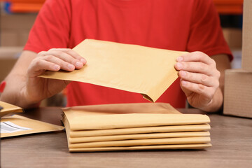 Fototapeta premium Post office worker with adhesive paper bags at counter indoors, closeup