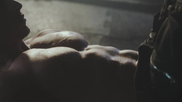 Extreme close-up shot of a young muscular man doing knee crunches on the floor during abs workout at at gym