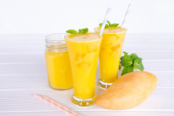 Fototapeta premium Mango smoothies yellow colorful fruit juice milkshake blend beverage healthy high protein the taste yummy In glass,drink to lose weight drink episode morning on white gray background. 
