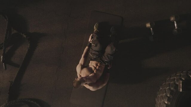 Top view of a strong and muscular man doing workout in the gymn while lying on floor