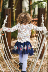 Preschool child playing on rope swing in beautiful tropical kindergarten yard.