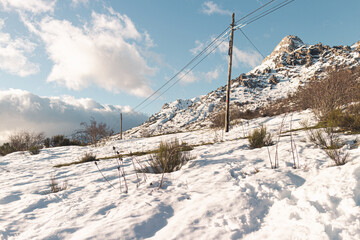 Natural view on a sunny day of snow-capped mountains with some electric power poles