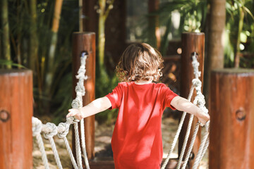 Preschool child playing on rope swing in beautiful tropical kindergarten yard.