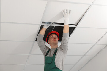 Suspended ceiling installation. Builder working with PVC tile - obrazy, fototapety, plakaty