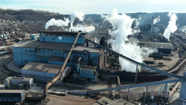Smoke and steam rising from smokestacks at American steel factory. Aerial shot of USS Steel mill manufacturing plant.