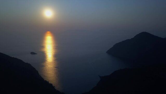 Rich gold and blue ocean sunset, seen from mountain island aerial