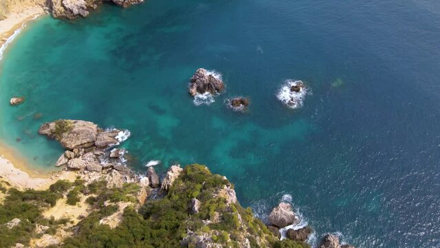 Aerial, tilt up view of rocky cliff beach with no people on Corfu, Greece, slow-motion