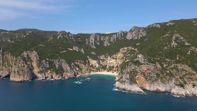 Aerial, far view of rocky cliff beach with no people on Corfu, Greece, slow-motion