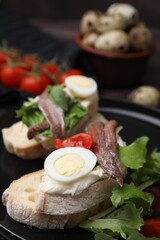 Fototapeta na wymiar Delicious bruschettas with anchovies, cream cheese, arugula, eggs and tomatoes on table, closeup
