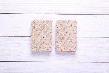 Tasty crispbreads on white wooden table, flat lay