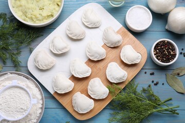 Fototapeta na wymiar Raw dumplings (varenyky) and ingredients on light blue table, flat lay