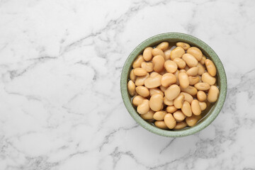 Bowl of canned kidney beans on white marble table, top view. Space for text