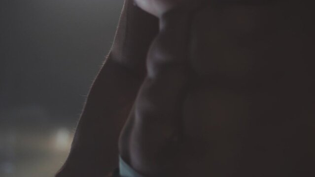 Close-up shot of an unrecognizable muscular strong man with six pack abs posing on camera at gym