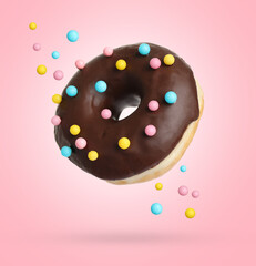 Delicious sweet donut falling on pink background