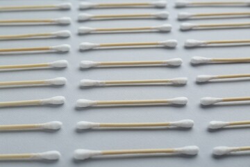 Many wooden cotton buds on light grey background, closeup