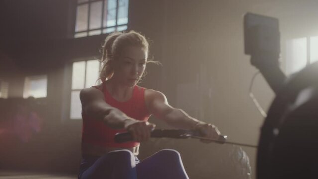 Female bodybuilder rowing in sport machine on gym training in club. Shot in slow-motion