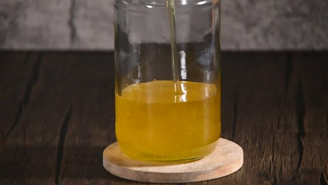 Home made clarified butter or also called as Ghee pouring in a glass storage container