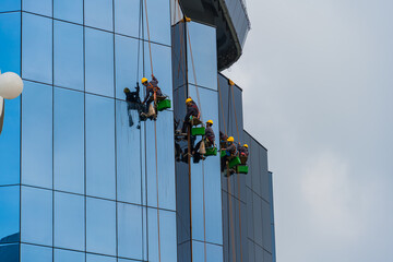 Group of workers cleaning glass windows service on high building or tower