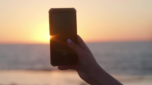 Woman Taking Video Of An Ocean Sunset With Mobile Phone, Rabat Morocco.